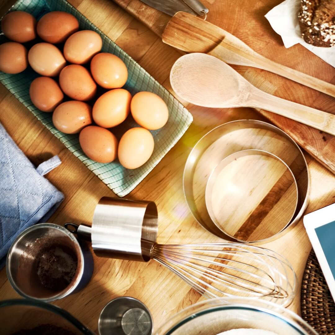 Some eggs in a tray and cooking tools such as spatula and rolls. 