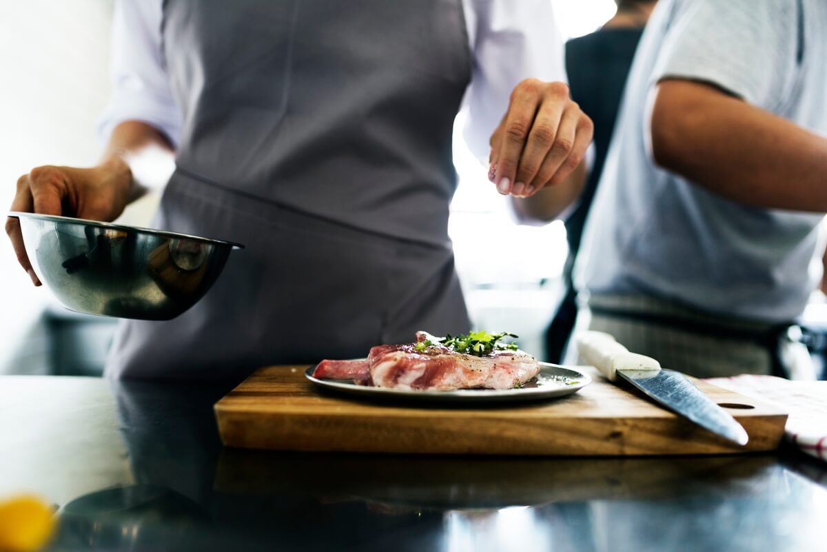 A chef adding seasons to a fresh beef.