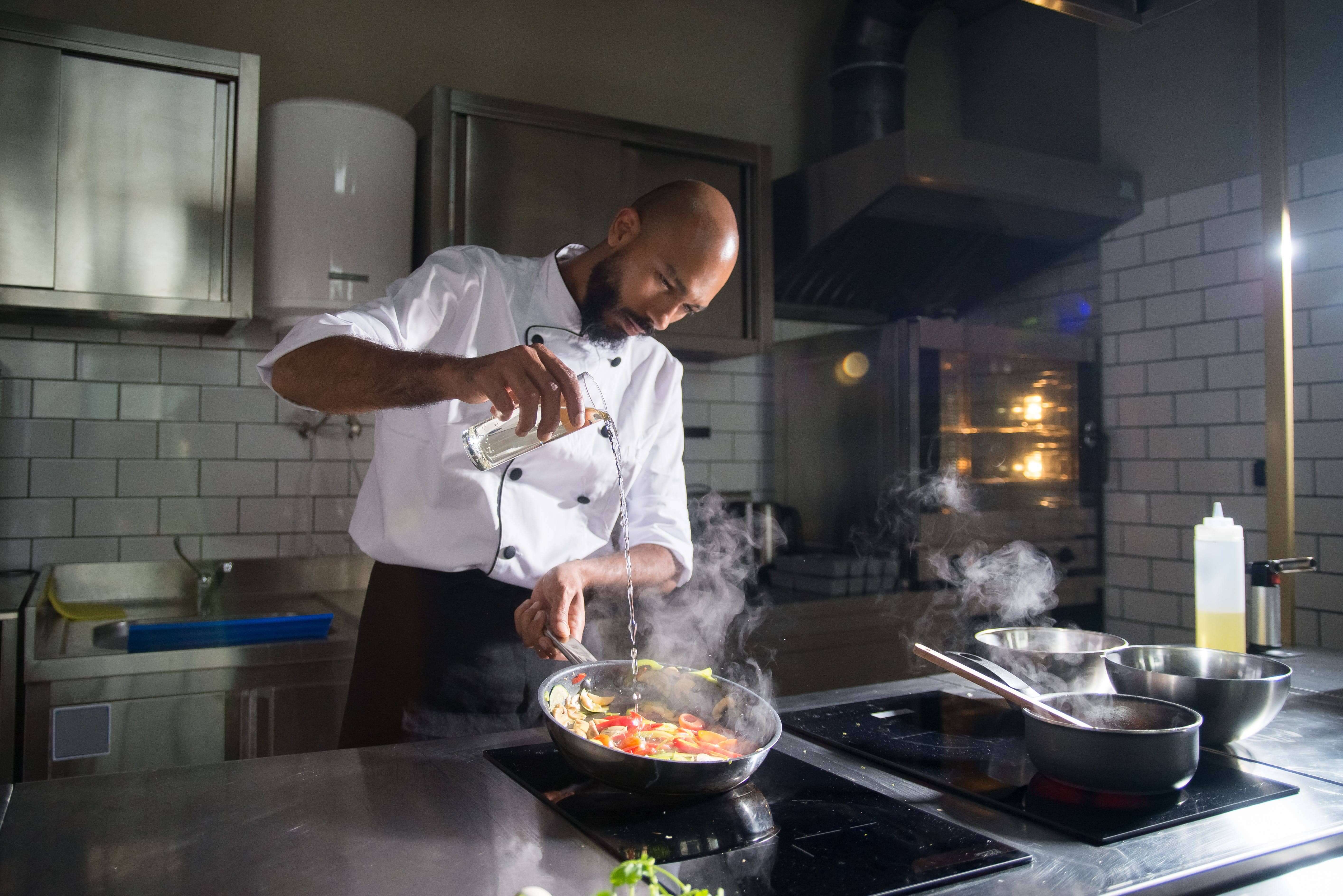 A chef mixing and garnishing food in the kitchen.